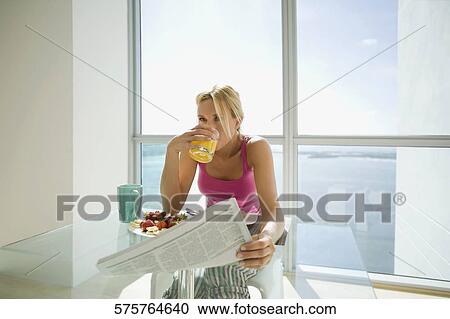 Mid adult woman holding a newspaper and drinking juice View Large Photo Image Stock Image - Mid adult woman holding a newspaper and drinking juice. Fotosearch