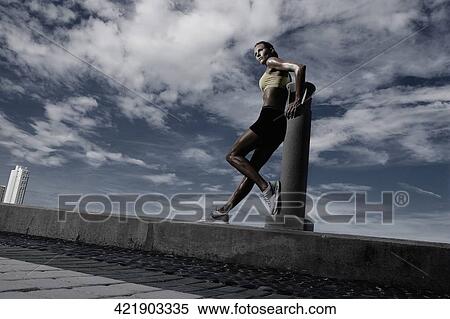 Stock Photography - Mid adult woman leaning against a column. Fotosearch