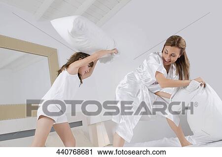 Mid adult woman pillow fighting with her daughter View Large Photo Image Stock Image - Mid adult woman pillow fighting with her daughter. Fotosearch