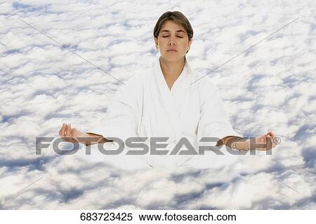 Mid adult woman practicing yoga on clouds View Large Photo Image Stock Photography - Mid adult woman practicing yoga on clouds. Fotosearch