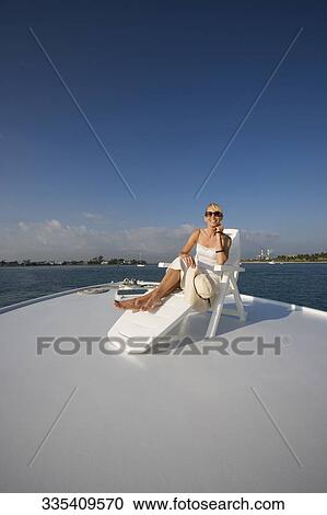 Mid adult woman resting on a deck chair and smiling View Large Photo Image Stock Image - Mid adult woman resting on a deck chair and smiling. Fotosearch