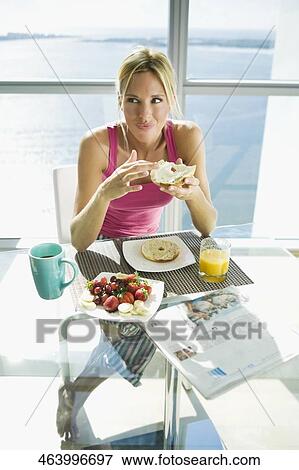 Mid adult woman sitting on a chair and holding a piece of bun View Large Photo Image Stock Photo - Mid adult woman sitting on a chair and holding a piece of bun. Fotosearch