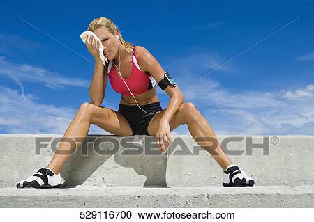 Mid adult woman sitting on a ledge View Large Photo Image Stock Image - Mid adult woman sitting on a ledge. Fotosearch