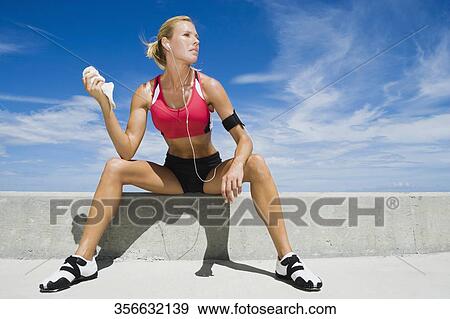 Mid adult woman sitting on a ledge View Large Photo Image Stock Photo - Mid adult woman sitting on a ledge. Fotosearch