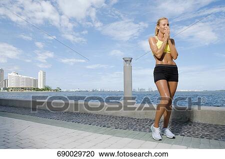 Stock Image - Mid adult woman standing at the riverside. Fotosearch