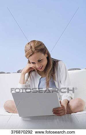 Mid adult woman working on a laptop and smiling View Large Photo Image Stock Image - Mid adult woman working on a laptop and smiling. Fotosearch