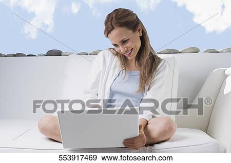 Mid adult woman working on a laptop and smiling View Large Photo Image Stock Photo - Mid adult woman working on a laptop and smiling. Fotosearch