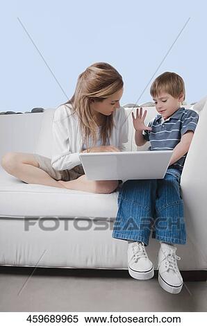 Mid adult woman working on a laptop with her son View Large Photo Image Stock Photography - Mid adult woman working on a laptop with her son. Fotosearch