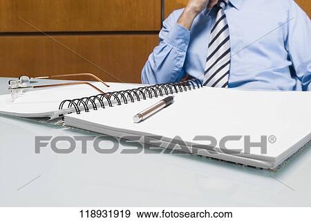 Mid section view of a businessman sitting in an office View Large Photo Image Stock Photo - Mid section view of a businessman sitting in an office. Fotosearch