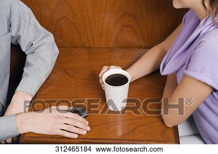 Mid section view of a couple sitting in a cafe View Large Photo Image Picture - Mid section view of a couple sitting in a cafe. Fotosearch