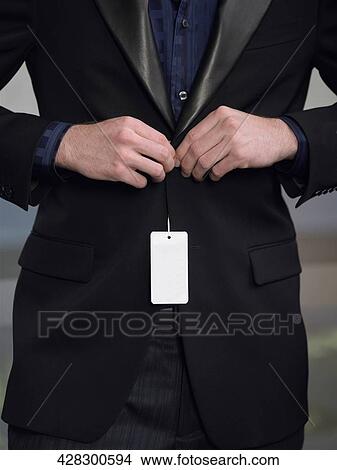 Mid section view of a man buttoning his coat View Large Photo Image Picture - Mid section view of a man buttoning his coat. Fotosearch