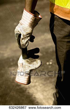 Mid section view of a manual worker holding a glove View Large Photo Image Stock Photo - Mid section view of a manual worker holding a glove. Fotosearch