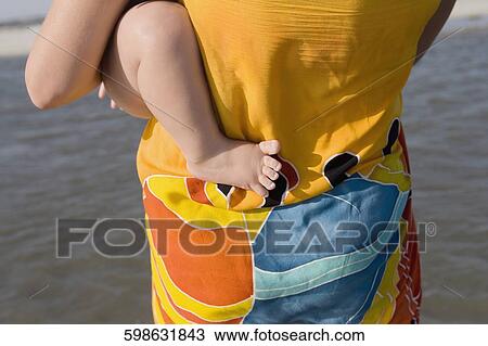 Mid section view of a woman carrying her baby View Large Photo Image Stock Image - Mid section view of a woman carrying her baby. Fotosearch