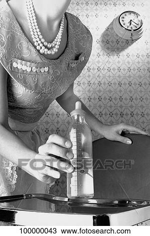Mid section view of a woman holding a baby bottle View Large Photo Image Stock Image - Mid section view of a woman holding a baby bottle. Fotosearch