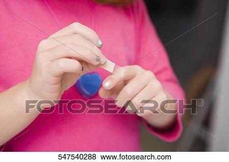 Mid section view of a woman putting a bandage on her finger View Large Photo Image Stock Photo - Mid section view of a woman putting a bandage on her finger. Fotosearch