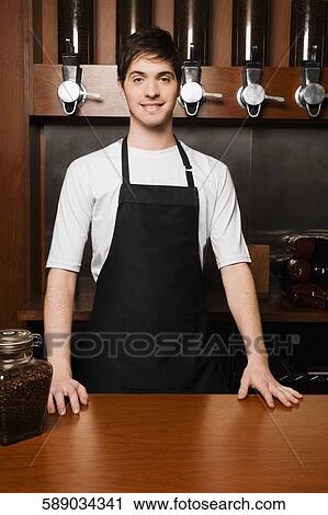 Owner standing at a cafe counter and smiling View Large Photo Image Stock Image - Owner standing at a cafe counter and smiling. Fotosearch