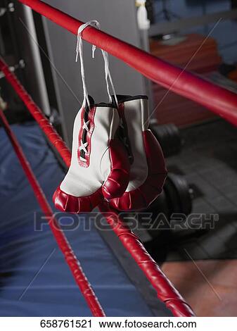 Stock Image - Pair of boxing gloves hanging on a rope of boxing ring. Fotosearch
