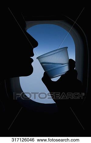 Passenger drinking water in an airplane View Large Photo Image Stock Photograph - Passenger drinking water in an airplane. Fotosearch