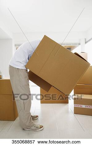 Person bending forward and holding a cardboard box View Large Photo Image Stock Photo - Person bending forward and holding a cardboard box. Fotosearch