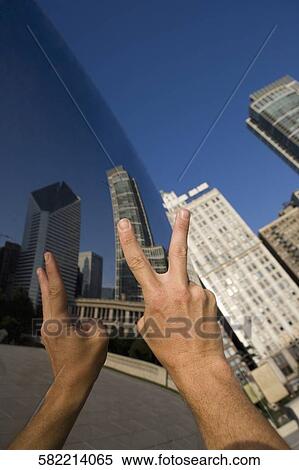 Stock Photography - Person showing a peace sign in front of a sculpture, Cloud Gate, Millennium Park, Chicago, Illinois, USA. Fotosearch