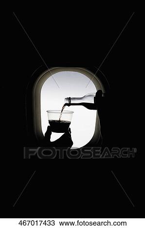 Stock Image - Person's hand pouring wine into a disposable cup. Fotosearch