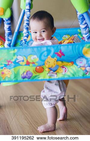 Stock Image - Portrait of a baby girl in a baby walker. Fotosearch