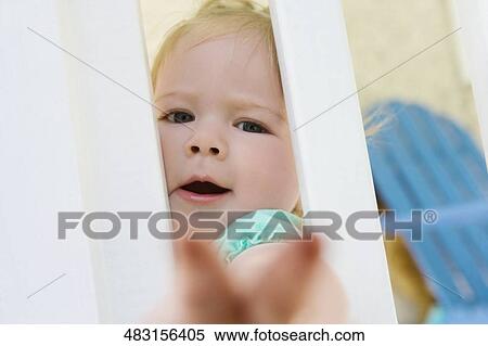 Stock Photography - Portrait of a baby girl looking through a window. Fotosearch