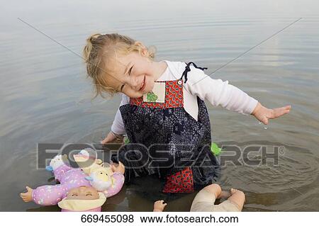 Portrait of a baby girl sitting in water with her dolls View Large Photo Image Stock Photo - Portrait of a baby girl sitting in water with her dolls. Fotosearch