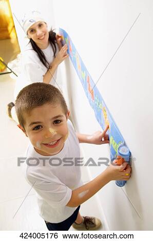 Portrait of a boy and his mother pasting a wallpaper on the wall View Large Photo Image Stock Photograph - Portrait of a boy and his mother pasting a wallpaper on the wall. Fotosearch