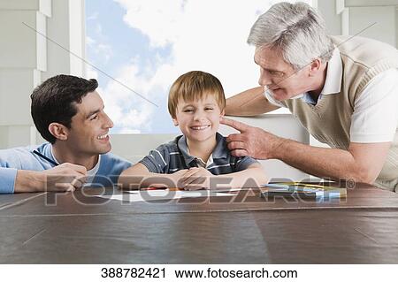 Stock Image - Portrait of a boy doing homework with the help of his father and grandfather. Fotosearch