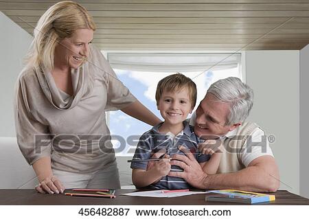 Stock Photo - Portrait of a boy doing homework with the help of his mother and grandfather. Fotosearch