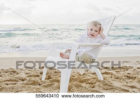 Stock Image - Portrait of a boy sitting on an adirondack chair and smiling. Fotosearch