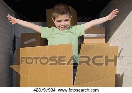 Portrait of a boy standing in a cardboard box with his arm outstretched View Large Photo Image Picture - Portrait of a boy standing in a cardboard box with his arm outstretched. Fotosearch