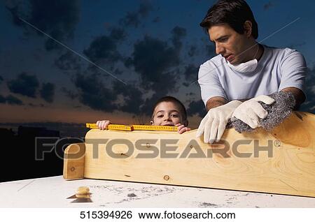 Portrait of a boy with his father holding a plank View Large Photo Image Stock Photograph - Portrait of a boy with his father holding a plank. Fotosearch