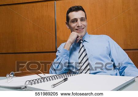 Portrait of a businessman sitting in an office and smiling View Large Photo Image Stock Photography - Portrait of a businessman sitting in an office and smiling. Fotosearch