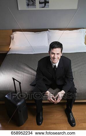 Portrait of a businessman sitting on the bed with his luggage View Large Photo Image Picture - Portrait of a businessman sitting on the bed with his luggage. Fotosearch
