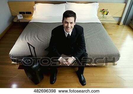 Portrait of a businessman sitting on the bed and smiling View Large Photo Image Stock Photo - Portrait of a businessman sitting on the bed and smiling. Fotosearch