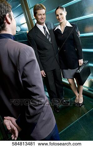Stock Image - Portrait of a businessman standing with a businesswoman and smiling. Fotosearch