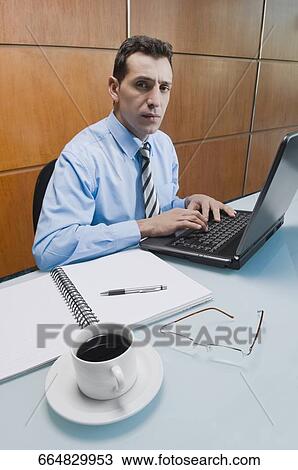 Portrait of a businessman working on a laptop in an office View Large Photo Image Stock Image - Portrait of a businessman working on a laptop in an office. Fotosearch
