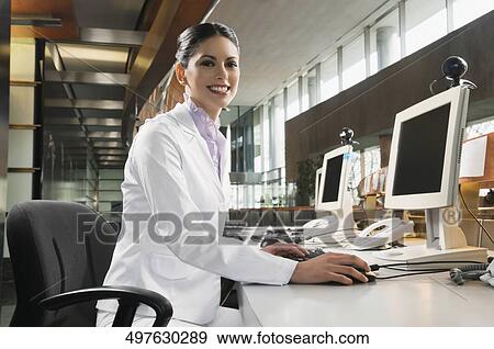 Portrait of a businesswoman working on a desktop PC and smiling View Large Photo Image Stock Photo - Portrait of a businesswoman working on a desktop PC and smiling. Fotosearch