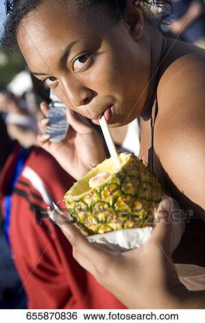 Portrait of a girl holding a mobile phone and drinking pineapple juice View Large Photo Image Stock Photograph - Portrait of a girl holding a mobile phone and drinking pineapple juice. Fotosearch