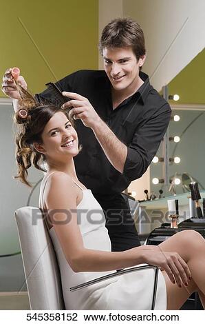 Portrait of a hairdresser adjusting the hair of a young woman View Large Photo Image Stock Image - Portrait of a hairdresser adjusting the hair of a young woman. Fotosearch