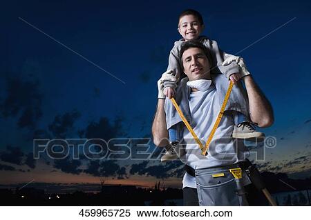 Stock Photography - Portrait of a mid adult man carrying his son on his shoulders. Fotosearch