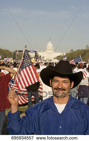 Stock Photo - Portrait of a mid adult man holding an American flag and smiling, Washington DC, USA. Fotosearch