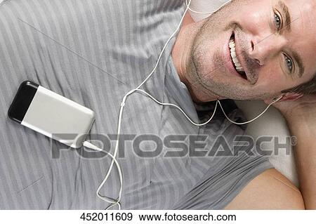 Portrait of a mid adult man listening to an MP3 player and smiling View Large Photo Image Stock Photo - Portrait of a mid adult man listening to an MP3 player and smiling. Fotosearch