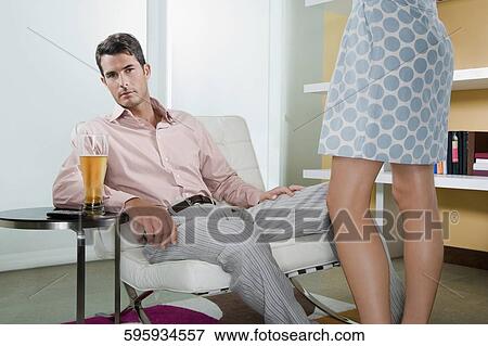 Portrait of a mid adult man sitting on a chair and a woman standing beside him View Large Photo Image Stock Photo - Portrait of a mid adult man sitting on a chair and a woman standing beside him. Fotosearch