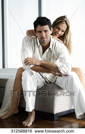 Portrait of a mid adult man with a mid adult woman sitting behind him and smiling View Large Photo Image Stock Photograph - Portrait of a mid adult man with a mid adult woman sitting behind him and smiling. Fotosearch