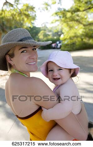Portrait of a mid adult woman carrying her baby girl and smiling View Large Photo Image Stock Photography - Portrait of a mid adult woman carrying her baby girl and smiling. Fotosearch