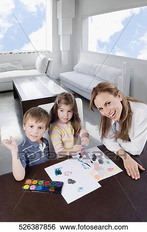 Portrait of a mid adult woman helping her children in painting View Large Photo Image Stock Photograph - Portrait of a mid adult woman helping her children in painting. Fotosearch