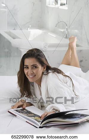 Portrait of a mid adult woman lying on the bed and reading a book View Large Photo Image Stock Photo - Portrait of a mid adult woman lying on the bed and reading a book. Fotosearch